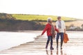 Senior Couple Hold Hands As They Walk Along Shoreline On Winter Beach Vacation Royalty Free Stock Photo