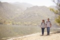 Senior couple hold hands hiking by mountain lake, front view Royalty Free Stock Photo