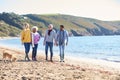 Senior Couple Hold Hands Walking Along Shoreline With Adult Offspring And Dog On Winter Beach Vacation Royalty Free Stock Photo