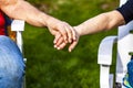 Senior couple holding hands while sitting together in the garden Royalty Free Stock Photo