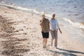 Senior couple holding hands and walking on sand at riverside Royalty Free Stock Photo