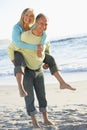 Senior Couple On Holiday With Husband Giving Wife Piggyback