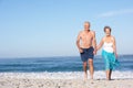 Senior Couple On Holiday Running Along Beach Royalty Free Stock Photo