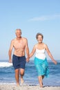 Senior Couple On Holiday Running Along Sandy Beach Royalty Free Stock Photo