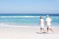 Senior Couple On Holiday Running Along Sandy Beach