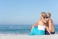 Senior Couple On Holiday Sitting On Sandy Beach Royalty Free Stock Photo