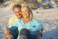 Senior Couple On Holiday Sitting On Sandy Beach Royalty Free Stock Photo