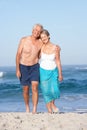 Senior Couple On Holiday Walking Along Sandy Beach Royalty Free Stock Photo