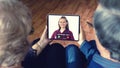 Senior couple at home holding digital tablet during video call with family doctor in telehealth