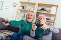 Senior couple at home playing video game holding joysticks in hands