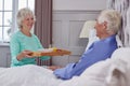 Senior Couple At Home With Woman Bringing Senior Man Breakfast In Bed On Tray Royalty Free Stock Photo