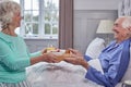 Senior Couple At Home With Woman Bringing Senior Man Breakfast In Bed On Tray Royalty Free Stock Photo