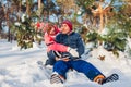 Senior couple hugging in winter forest. Man and woman sitting in snow and having fun on Valentine`s Day