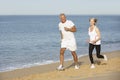Senior Couple Jogging Along Beach Royalty Free Stock Photo