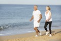 Senior Couple Jogging Along Beach Royalty Free Stock Photo