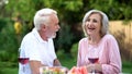 Senior couple laughing at dining table, telling funny jokes, remembering moments Royalty Free Stock Photo