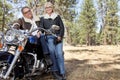 Senior couple lean on motorcycle in forest Royalty Free Stock Photo