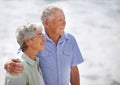 Senior, couple and look happy at beach for retirement vacation or anniversary to relax with love, care and commitment Royalty Free Stock Photo