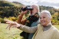 Senior couple looking at view trough binoculars on autumn walk. Royalty Free Stock Photo