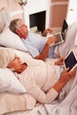 Senior Couple Lying In Bed Using Digital Devices Royalty Free Stock Photo