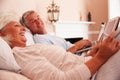 Senior Couple Lying In Bed Using Digital Devices Royalty Free Stock Photo