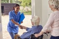 Senior Couple With Man In Wheelchair Greeting Female Nurse Or Care Worker Making Home Visit At Door Royalty Free Stock Photo