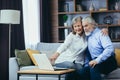 Senior couple man and woman shopping online browsing laptop in home. Elderly family Happy retired couple using computerooking at