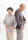 senior couple measuring belly with measurement tape