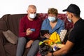 Senior couple in medical masks orders by courier and paid by credit card. Pandemic, online concept