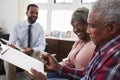 Senior Couple Meeting With Male Financial Advisor At Home And Signing Document Royalty Free Stock Photo