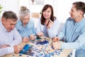 Senior couple and middle age couple solving jigsaw puzzle together with family at home Royalty Free Stock Photo
