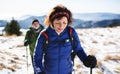 Senior couple with nordic walking poles hiking in snow-covered winter nature.