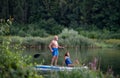 Senior couple paddleboarding on lake in summer.
