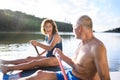 Senior couple paddleboarding on lake in summer.