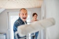 Senior couple painting walls in new home, having fun. Relocation concept. Royalty Free Stock Photo