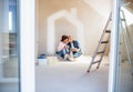 Senior couple painting walls in new home, kissing. Relocation concept.