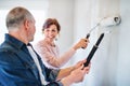 Senior couple painting walls in new home, relocation concept.