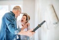 Senior couple painting walls in new home, relocation concept.