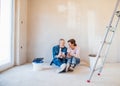 Senior couple painting walls in new home, resting. Relocation concept. Royalty Free Stock Photo