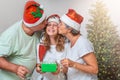 Senior couple parents kissing teenage daughter for Christmas Royalty Free Stock Photo