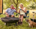 Senior Couple With Pet Dog Camping In RV Eating Bacon And Eggs For Breakfast Outdoors On Fire Royalty Free Stock Photo