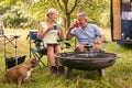 Senior Couple With Pet Dog Camping In RV Eating Bacon And Eggs For Breakfast Outdoors On Fire Royalty Free Stock Photo