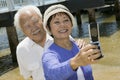 Senior couple photographing themselves by pier