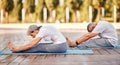 Senior couple practicing Paschimottanasana while doing yoga together in park on sunny morning Royalty Free Stock Photo