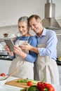 Senior couple preparing salad using tablet ordering food in grocery e shop. Royalty Free Stock Photo