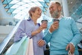 Senior couple riding down shopping mall escalator Royalty Free Stock Photo