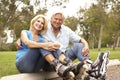 Senior Couple Putting On In Line Skates In Park