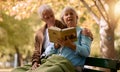 Senior couple, reading book and relax outdoor on bench in summer for retirement freedom, travel adventure and happy Royalty Free Stock Photo