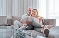 Senior couple reading book on sofa together enjoying weekend, freedom and retirement at home. Love, relaxation and Royalty Free Stock Photo