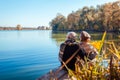 Senior couple relaxing by autumn lake. Happy man and woman enjoying nature and hugging sitting on pier Royalty Free Stock Photo